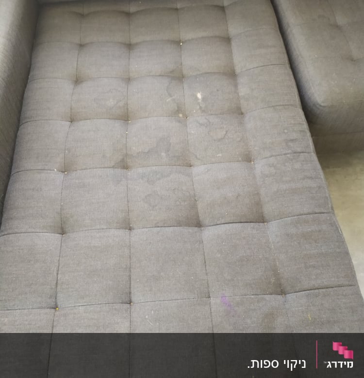 ספה אפורה עם כתמים ולכלוך על המושב